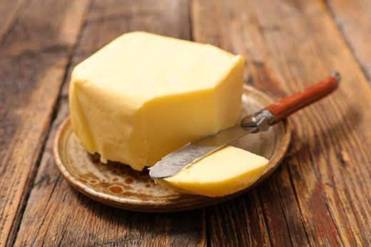Teller mit Butter und Messer auf einem Holztisch.